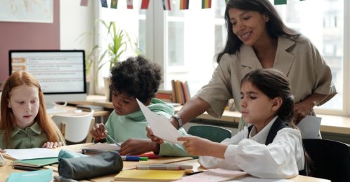 An English teacher passes papers to students. (Shutterstock Photo)