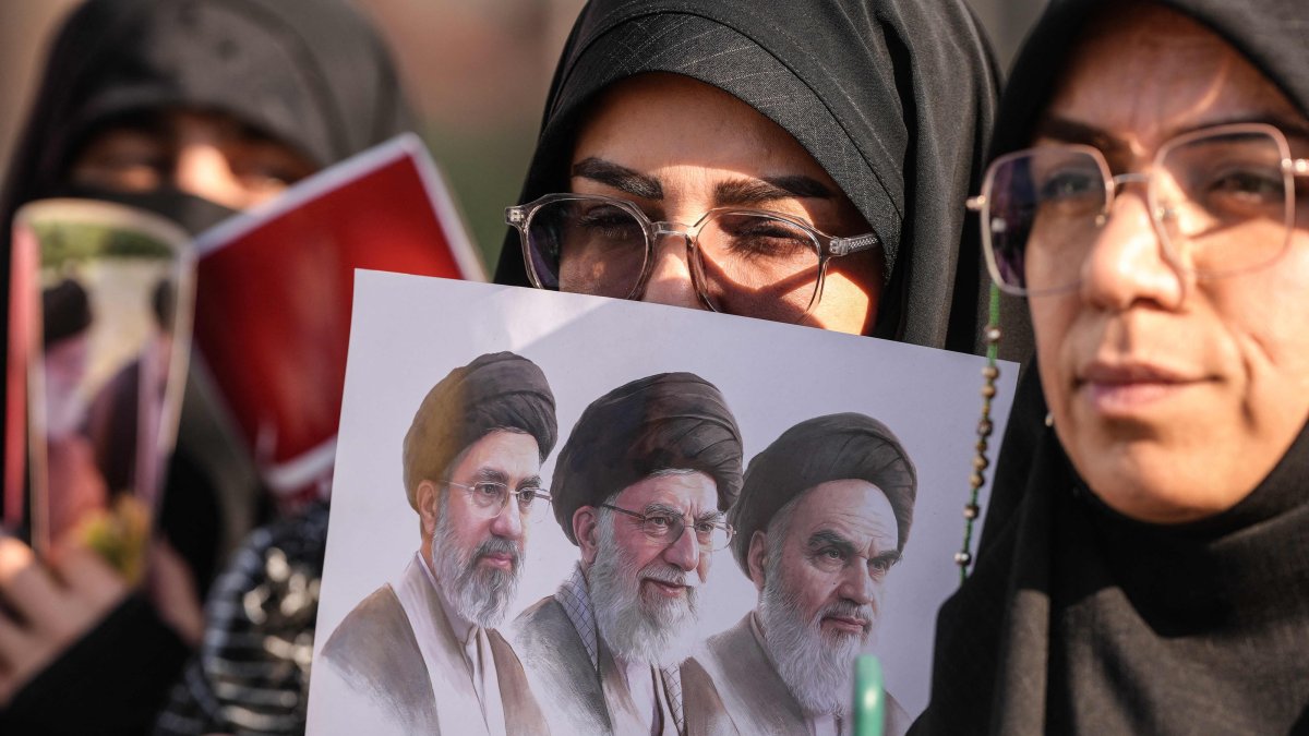 Mourners hold a placard depicting (from R) the late founder of the Islamic Republic, Ayatollah Ruhollah Khomeini, slain supreme leader Ayatollah Ali Khamenei, and current supreme leader Mojtaba Khamenei during a funeral procession for Ayatollah Ali Khamenei in Najaf on July 8, 2026. (AFP Photo)