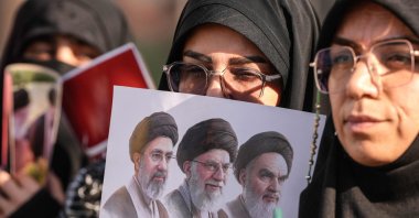 Mourners hold a placard depicting (from R) the late founder of the Islamic Republic, Ayatollah Ruhollah Khomeini, slain supreme leader Ayatollah Ali Khamenei, and current supreme leader Mojtaba Khamenei during a funeral procession for Ayatollah Ali Khamenei in Najaf on July 8, 2026. (AFP Photo)