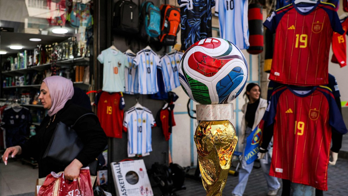 A woman walks past a replica of the 2026 FIFA World Cup trophy and official match ball outside a sports apparel shop selling World Cup-affiliated merchandise in the city of Hebron, West Bank, Palestine, July 8, 2026. (AFP Photo)