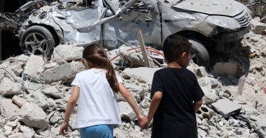 Children walk next to a damaged car following an Israeli strike in the village of Maaroub, southern Lebanon, June 15, 2026. (EPA Photo)