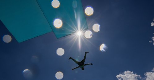 A person jumps off the diving platform at the Stadionbad public swimming pool on a hot, sunny day in Cologne, Germany, Thursday, June 18, 2026. (Rolf Vennenbernd/dpa via AP)