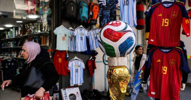 A woman walks past a replica of the 2026 FIFA World Cup trophy and official match ball outside a sports apparel shop selling World Cup-affiliated merchandise in the city of Hebron, West Bank, Palestine, July 8, 2026. (AFP Photo)