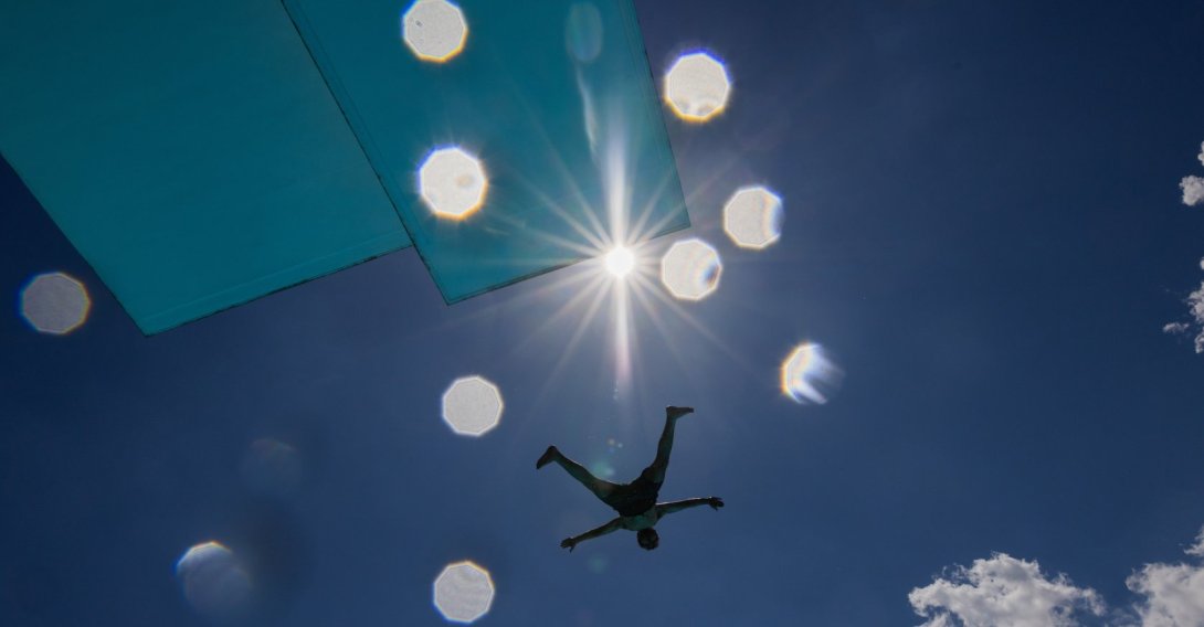 A person jumps off the diving platform at the Stadionbad public swimming pool on a hot, sunny day in Cologne, Germany, Thursday, June 18, 2026. (Rolf Vennenbernd/dpa via AP)