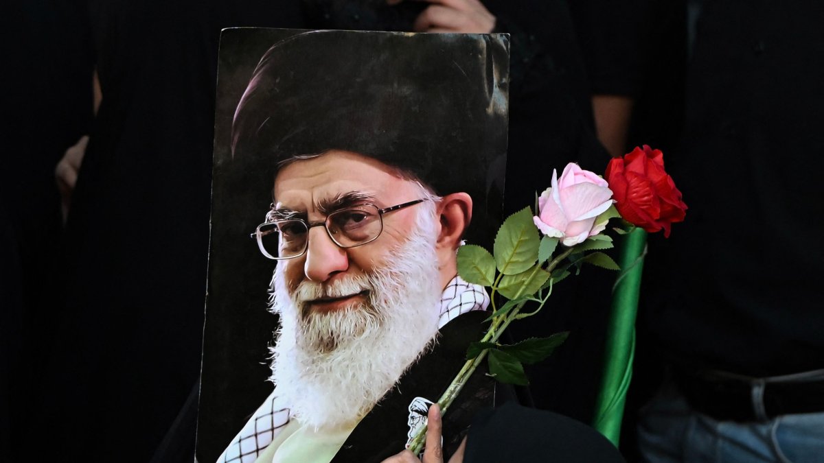 A woman holds flowers and a portrait of Iran's slain supreme leader Ali Khamenei as mourners gather ahead of his funeral procession and members of his family, before he is buried at the Shrine of Imam Reza, Mashhad, Iran, July 9, 2026. (AFP Photo)