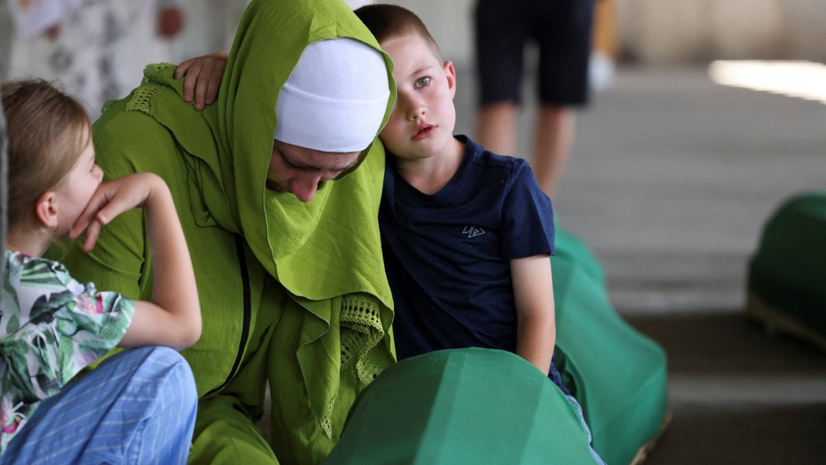 A Bosnian woman, Mediha Dzozic, accompanied by her son Almin, cries near the coffin of her father, who is one of the 10 victims who will be buried on July 11 during a mass funeral marking the 31st anniversary of the Srebrenica genocide, Potocari, Bosnia- Herzegovina, July 9, 2026. (Reuters Photo)