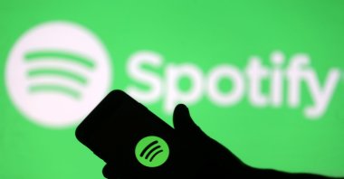This photo illustration shows a smartphone in front of a screen projection of the Spotify logo, April 1, 2018. (Reuters File Photo)