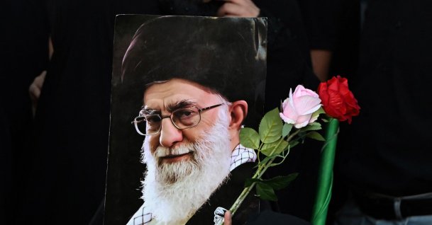 A woman holds flowers and a portrait of Iran's slain supreme leader Ali Khamenei as mourners gather ahead of his funeral procession and members of his family, before he is buried at the Shrine of Imam Reza, Mashhad, Iran, July 9, 2026. (AFP Photo)