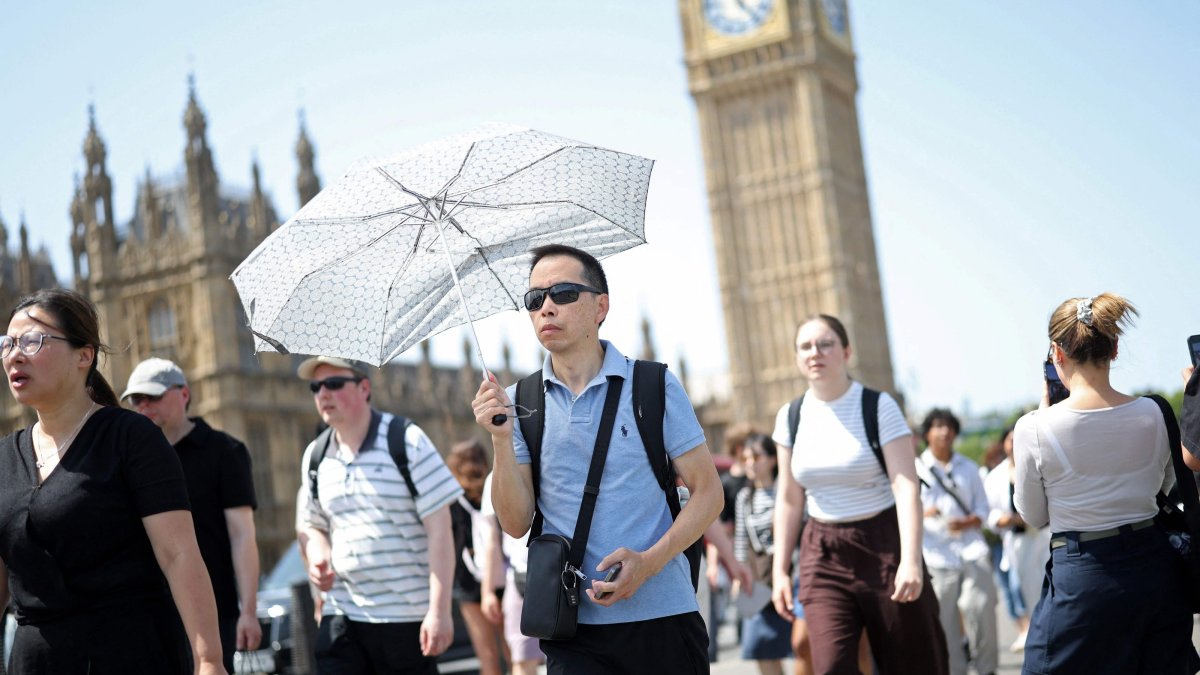 A person uses an umbrella to shelter from the direct sun on a hot summer's day in London, U.K., June 23, 2026. (AFP Photo)
