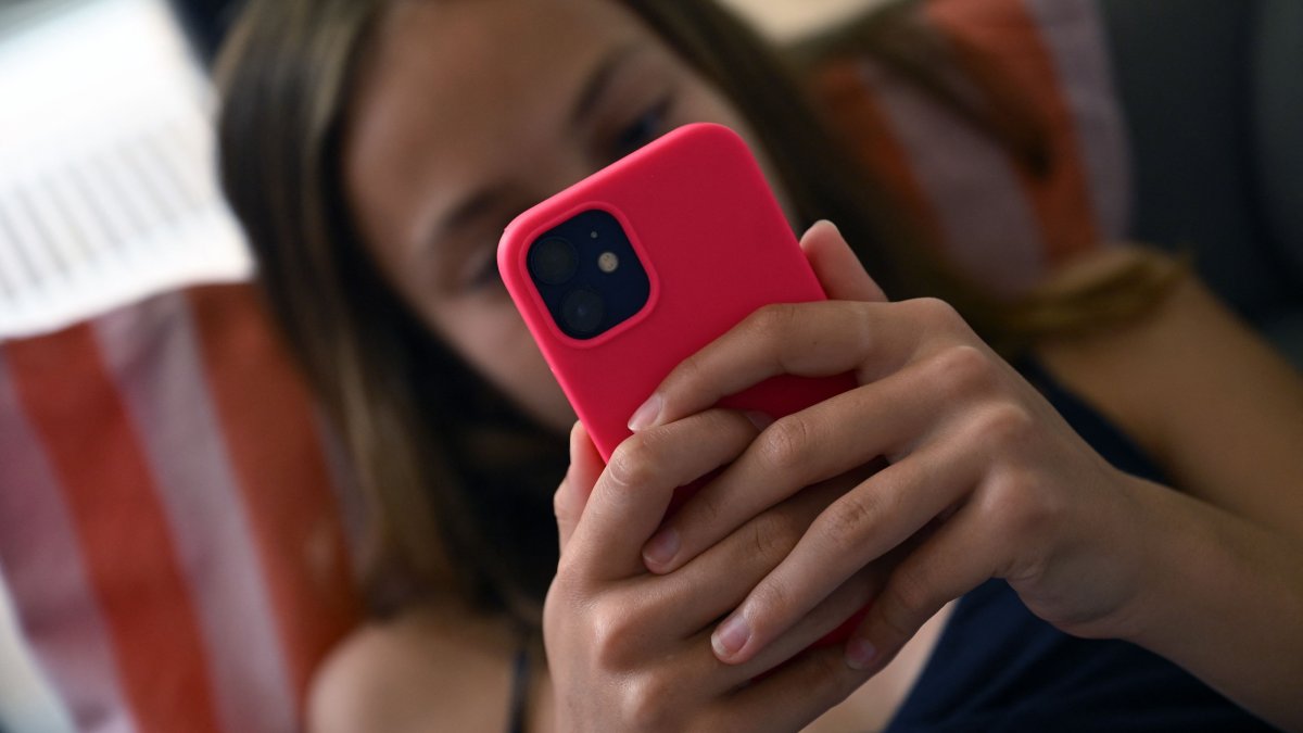 A teenager looks at her smartphone in Brussels, Belgium, July 7, 2026. (AFP Photo)