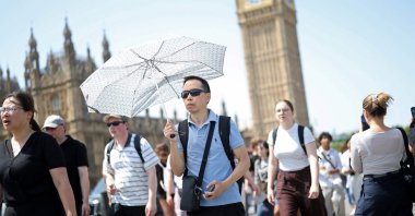 A person uses an umbrella to shelter from the direct sun on a hot summer's day in London, U.K., June 23, 2026. (AFP Photo)