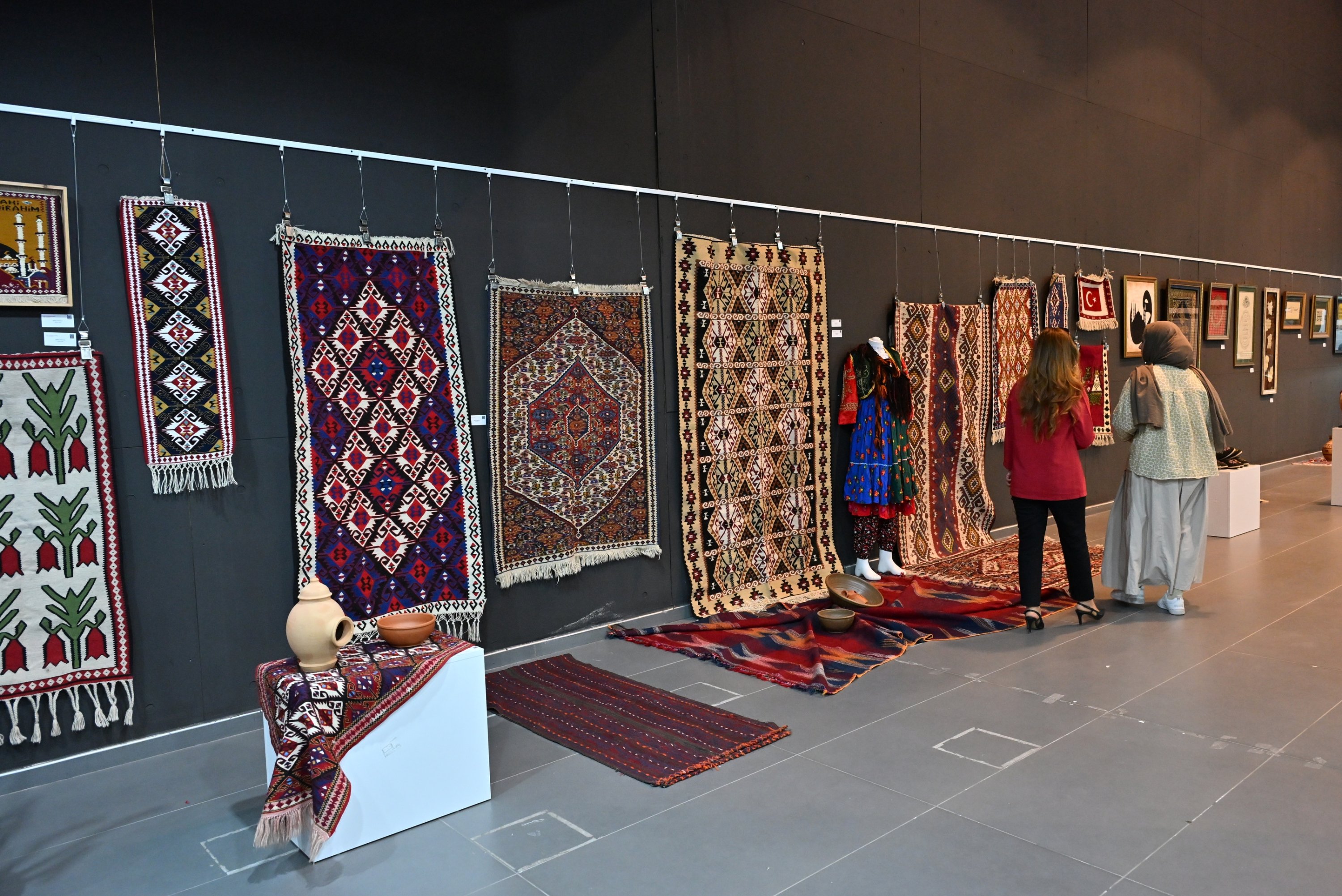 Visitors examine handcrafted carpets on display at the