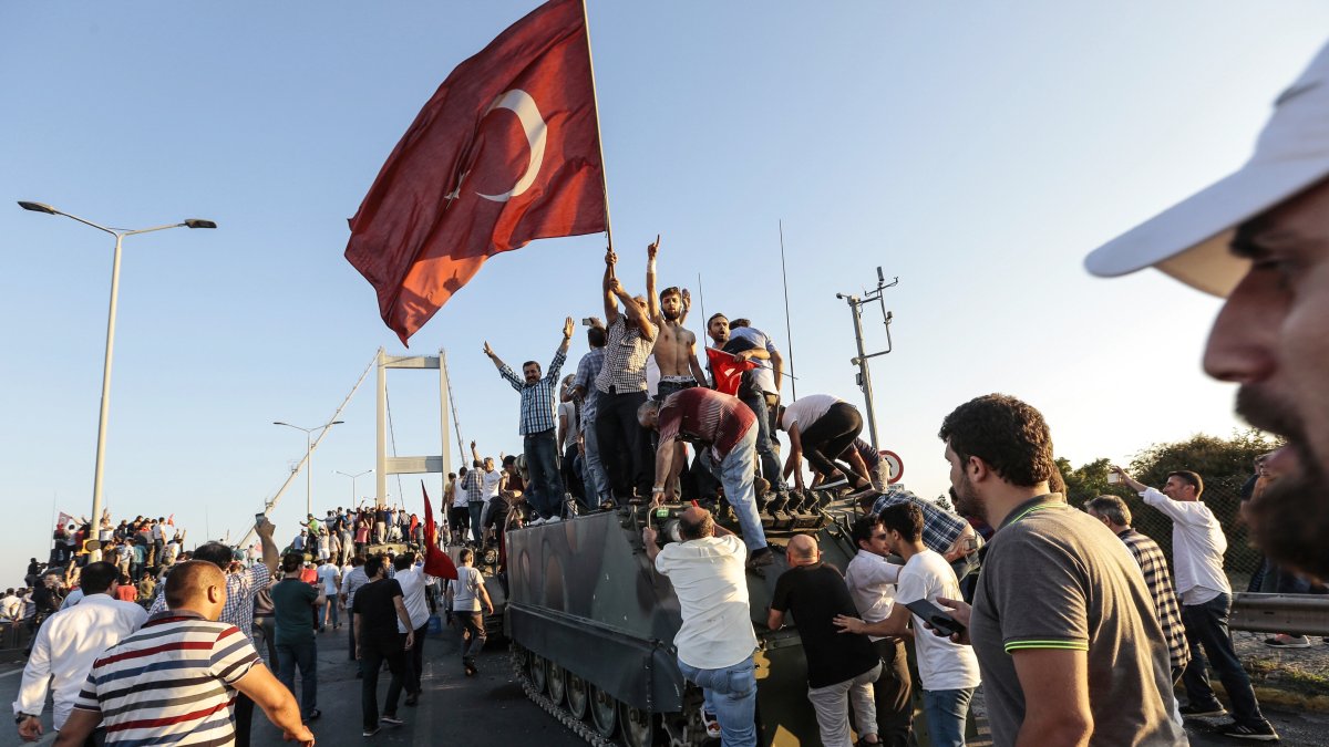 People gather and wave flags around a tank after soldiers involved in the coup attempt surrendered on the Bosporus Bridge, Istanbul, Türkiye, July 16, 2016. (Getty Images Photo)