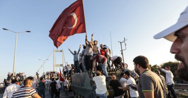 People gather and wave flags around a tank after soldiers involved in the coup attempt surrendered on the Bosporus Bridge, Istanbul, Türkiye, July 16, 2016. (Getty Images Photo)