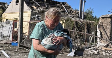 A woman carries a cat near a house damaged by a Russian airstrike in Zaporizhzhia, Ukraine, July 13, 2026. (Reuters Photo)