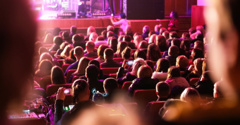 People watch a performance in an auditorium. (Shutterstock Photo)