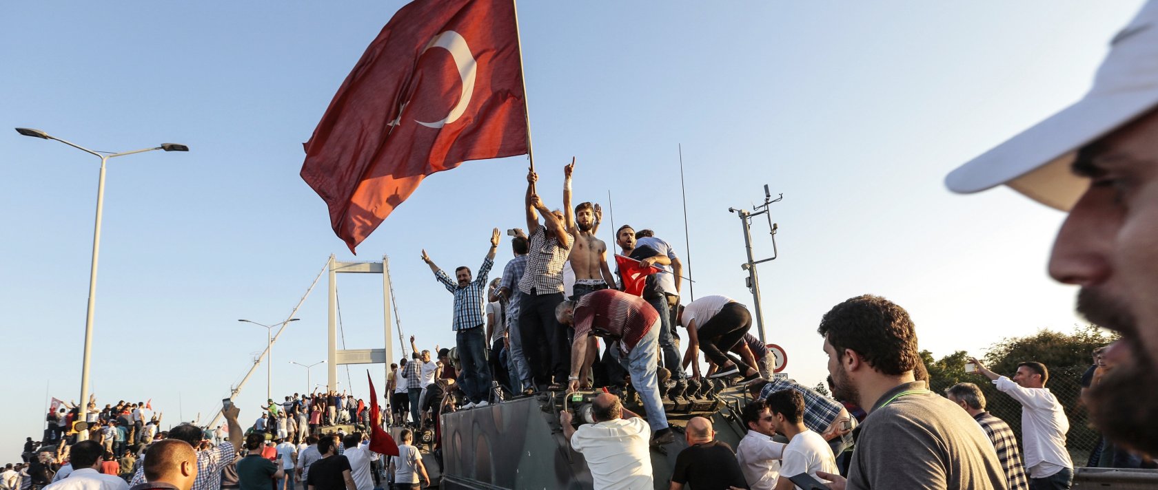 People gather and wave flags around a tank after soldiers involved in the coup attempt surrendered on the Bosporus Bridge, Istanbul, Türkiye, July 16, 2016. (Getty Images Photo)