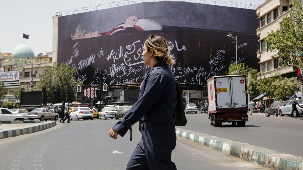 An Iranian woman walks next to a huge anti-US billboard featuring U.S. president Donald Trump in a coffin at the Enqelab Square in Tehran, Iran, July 15, 2026. (AA Photo)