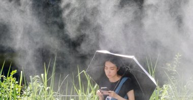 A woman takes a break under a cooling mist during a heat wave, Tokyo, Japan, July 15, 2026. (Reuters Photo)