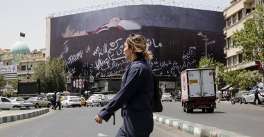 An Iranian woman walks next to a huge anti-US billboard featuring U.S. president Donald Trump in a coffin at the Enqelab Square in Tehran, Iran, July 15, 2026. (AA Photo)