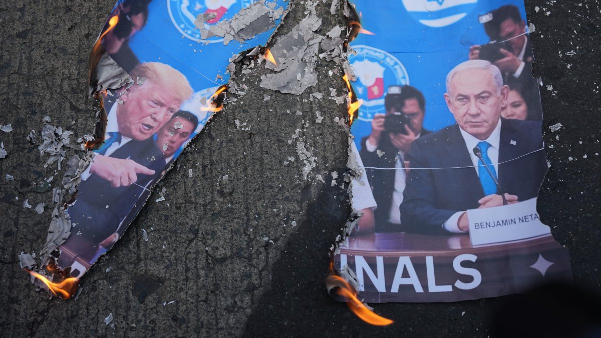 A picture of U.S. President Donald Trump (L) and Israeli Prime Minister Benjamin Netanyahu burns as protesters hold a rally to condemn the Iran war in Manila, Philippines, March 6, 2026. (AP Photo)