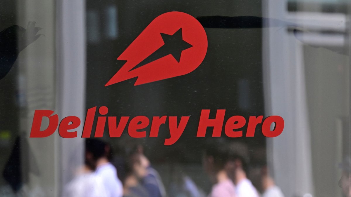 People are reflected in a window with the company logo at the headquarters of German food delivery group Delivery Hero, Berlin, Germany, July 16, 2026. (AFP Photo)