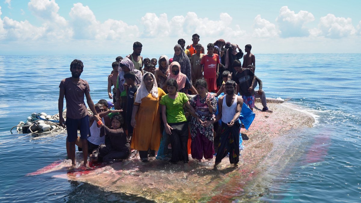 Rohingya survivors stand on a capsized wooden boat as they wait for rescuers to evacuate them in the waters off West Aceh, Indonesia, March 21, 2024. (EPA Photo)