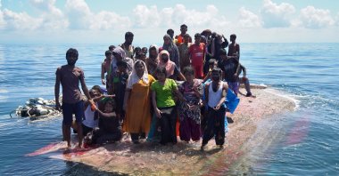 Rohingya survivors stand on a capsized wooden boat as they wait for rescuers to evacuate them in the waters off West Aceh, Indonesia, March 21, 2024. (EPA Photo)