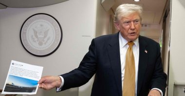 U.S. President Donald Trump holds up a copy of his Truth Social post about Air Force One as he speaks with the media shortly after departure from Mildenhall Air Force Base, U.K., July 8, 2026. (AFP Photo)