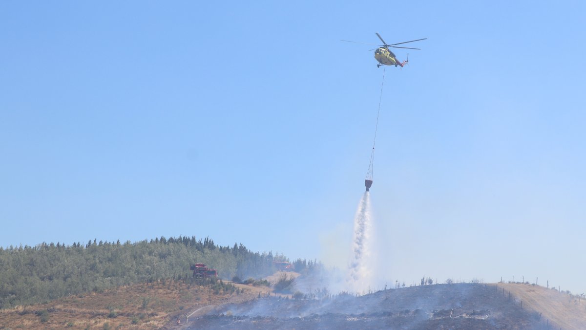 A firefighting helicopter drops water over a forest fire that spread from a grassland area, Izmir, Türkiye, July 15, 2026. (AA Photo)