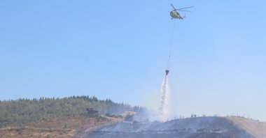 A firefighting helicopter drops water over a forest fire that spread from a grassland area, Izmir, Türkiye, July 15, 2026. (AA Photo)