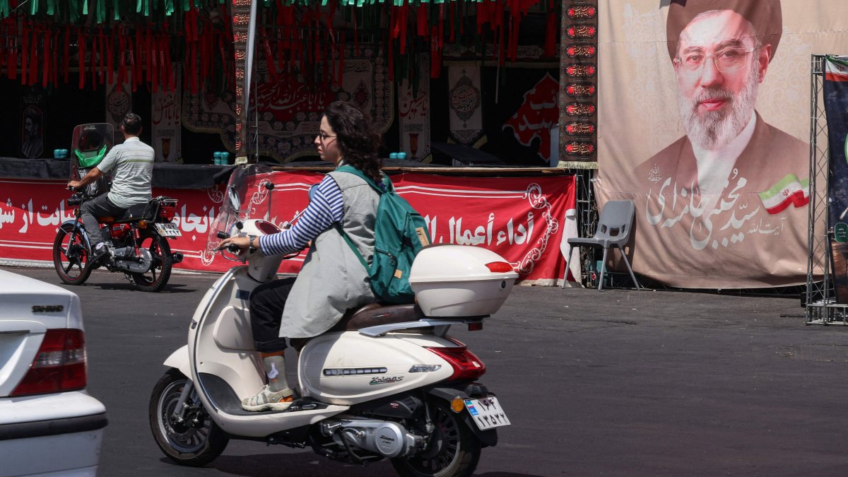 A woman rides a motorcycle past a banner of Iran's Supreme Leader Mojtaba Khamenei at Valiasr Square in Tehran, Iran, July 19, 2026. (AFP Photo)