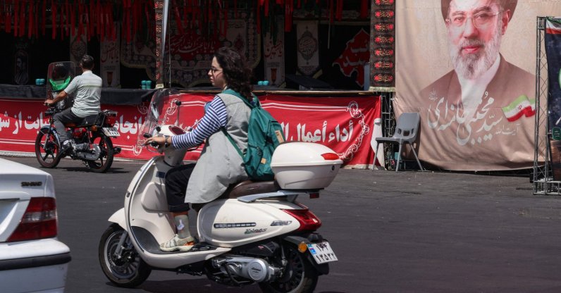 A woman rides a motorcycle past a banner of Iran's Supreme Leader Mojtaba Khamenei at Valiasr Square in Tehran, Iran, July 19, 2026. (AFP Photo)