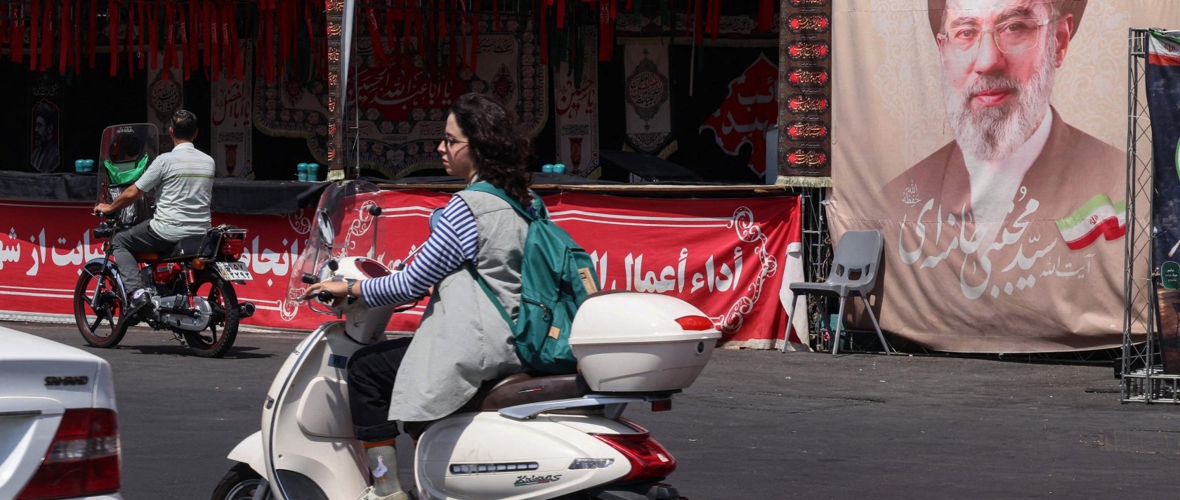 A woman rides a motorcycle past a banner of Iran's Supreme Leader Mojtaba Khamenei at Valiasr Square in Tehran, Iran, July 19, 2026. (AFP Photo)