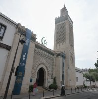 People walk past the Grand Mosque of Paris, where a banner reads, "100 years of light, a century of history, spirituality and dialogue," marking its 100th anniversary, Paris, France, July 17, 2026. (AP Photo)