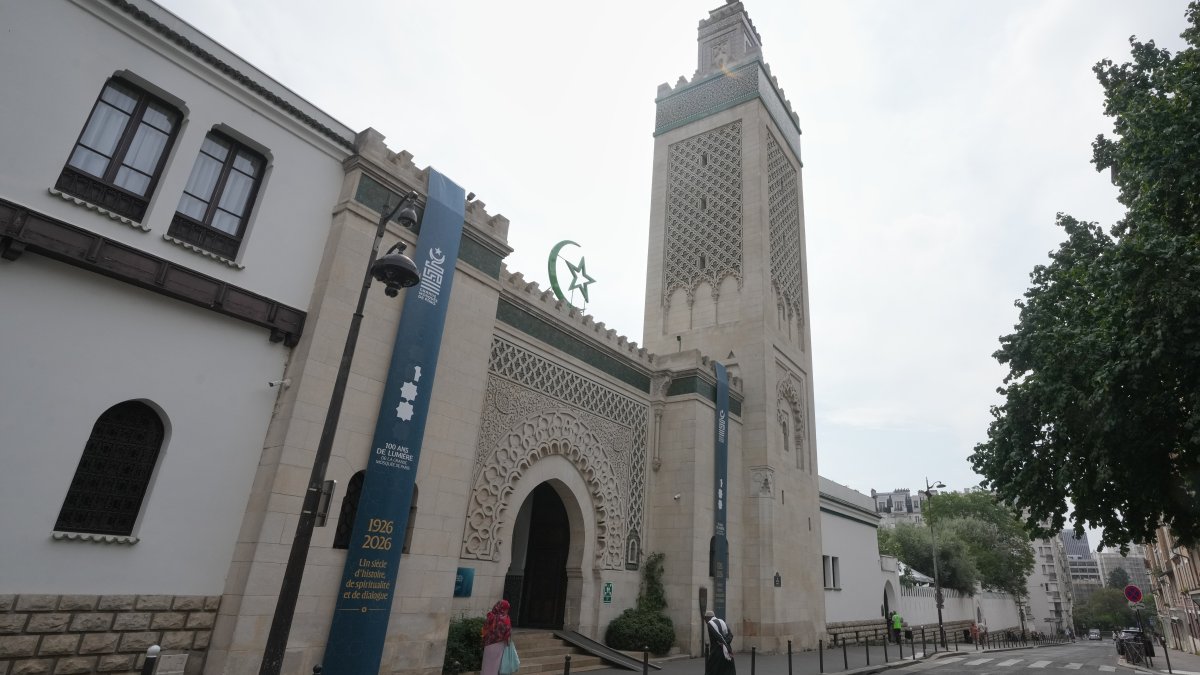 People walk past the Grand Mosque of Paris, where a banner reads, "100 years of light, a century of history, spirituality and dialogue," marking its 100th anniversary, Paris, France, July 17, 2026. (AP Photo)