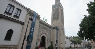 People walk past the Grand Mosque of Paris, where a banner reads, "100 years of light, a century of history, spirituality and dialogue," marking its 100th anniversary, Paris, France, July 17, 2026. (AP Photo)