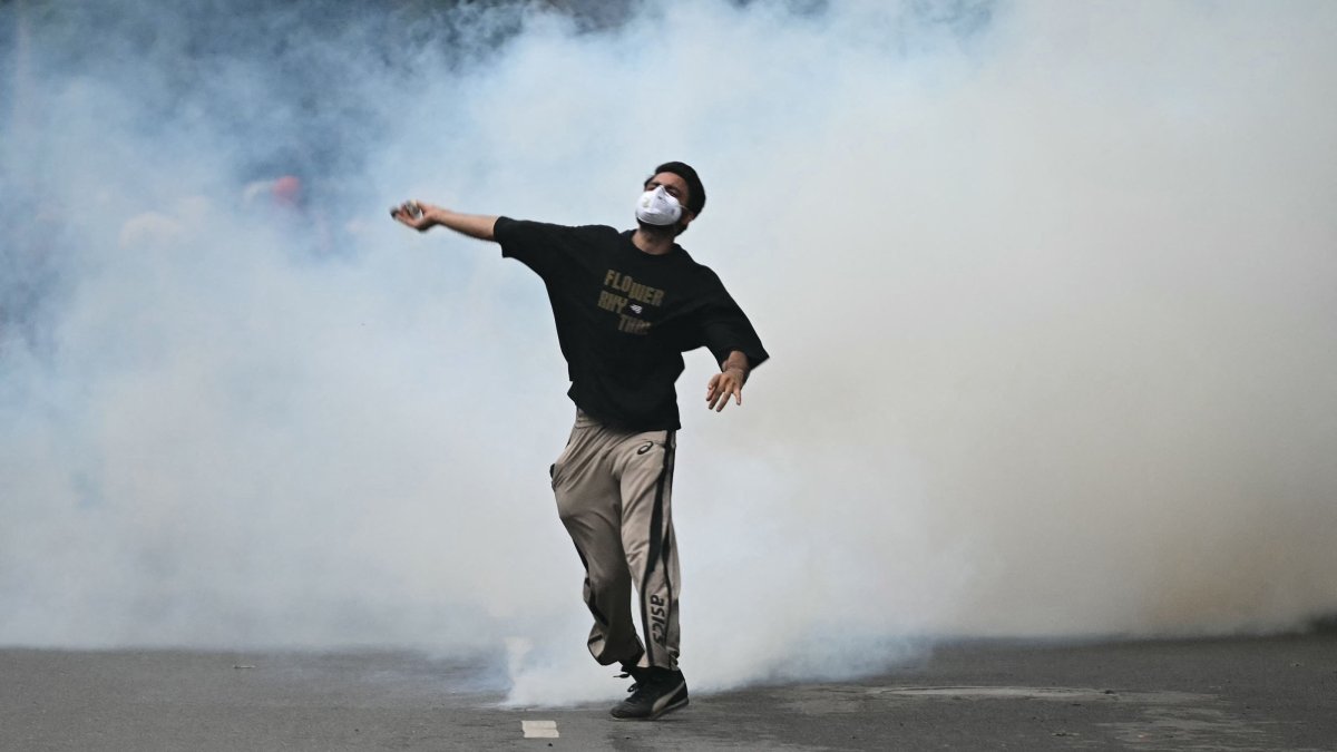 A protester throws back a tear gas canister fired by Rapid Action Force (RAF) personnel to disperse supporters of the Cockroach Janta Party (CJP), during a protest demanding the resignation of India's Education Minister Dharmendra Pradhan over alleged NEET exam irregularities in New Delhi, India, July 20, 2026. (AFP Photo)