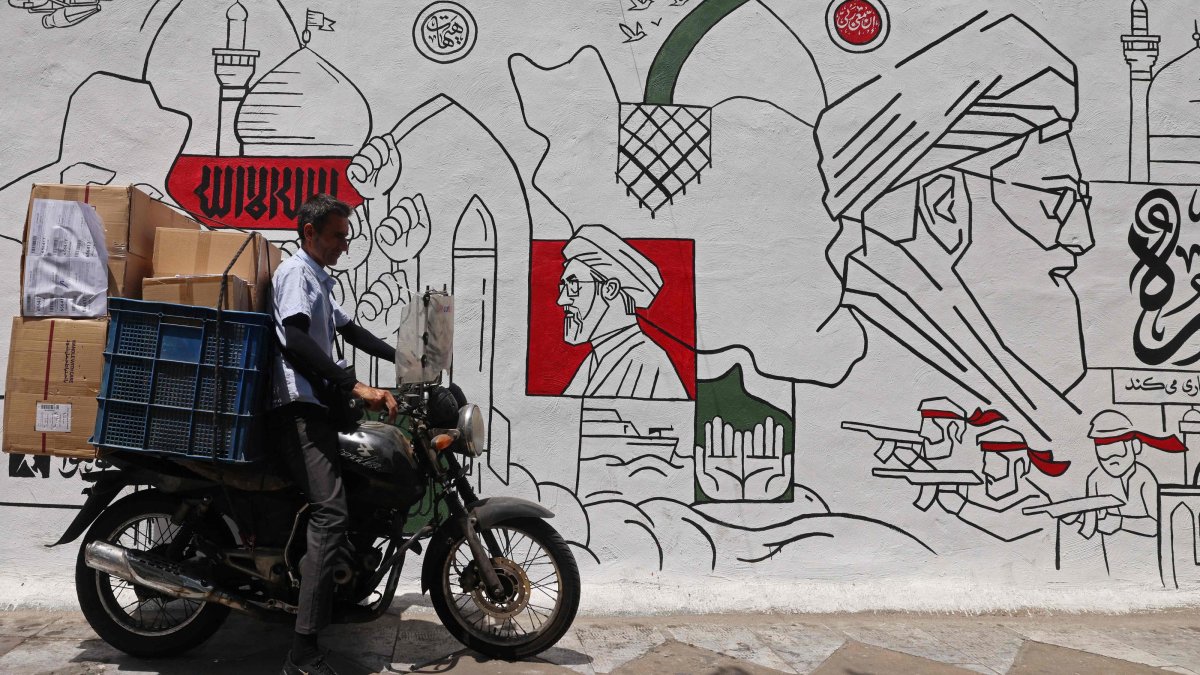 A motorist parks his bike in front of a wall mural along the street in Tehran, Iran, July 21, 2026. (AFP Photo)