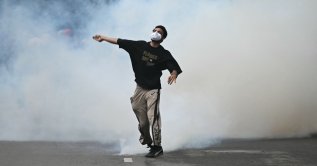 A protester throws back a tear gas canister fired by Rapid Action Force (RAF) personnel to disperse supporters of the Cockroach Janta Party (CJP), during a protest demanding the resignation of India's Education Minister Dharmendra Pradhan over alleged NEET exam irregularities in New Delhi, India, July 20, 2026. (AFP Photo)