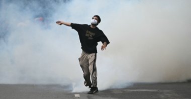 A protester throws back a tear gas canister fired by Rapid Action Force (RAF) personnel to disperse supporters of the Cockroach Janta Party (CJP), during a protest demanding the resignation of India's Education Minister Dharmendra Pradhan over alleged NEET exam irregularities in New Delhi, India, July 20, 2026. (AFP Photo)