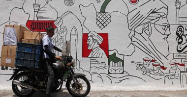 A motorist parks his bike in front of a wall mural along the street in Tehran, Iran, July 21, 2026. (AFP Photo)