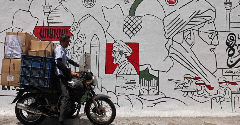 A motorist parks his bike in front of a wall mural along the street in Tehran, Iran, July 21, 2026. (AFP Photo)