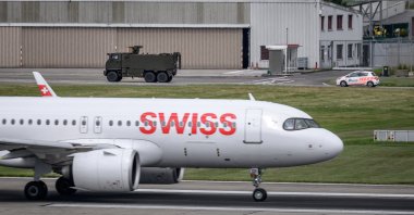 A Swiss Army vehicle and a police car pass behind the tail of a Swiss International Air Lines aircraft during a patrol on the tarmac at Geneva Airport ahead of the upcoming G7 summit in nearby Evian, in Geneva, June 11, 2026. (AFP File Photo)