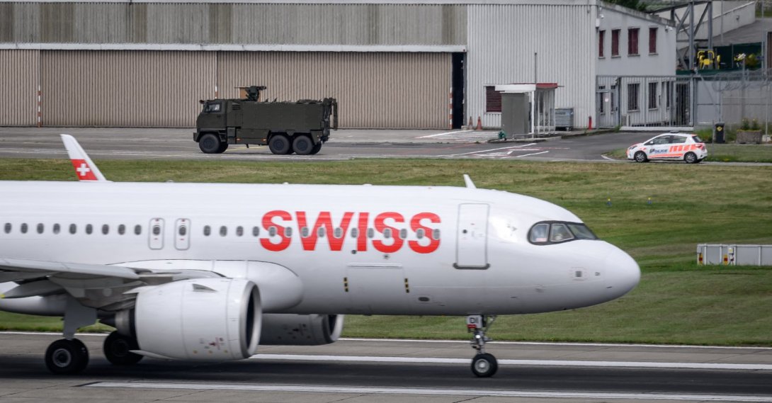 A Swiss Army vehicle and a police car pass behind the tail of a Swiss International Air Lines aircraft during a patrol on the tarmac at Geneva Airport ahead of the upcoming G7 summit in nearby Evian, in Geneva, June 11, 2026. (AFP File Photo)