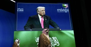 Crown Prince and Prime Minister of the Kingdom of Saudi Arabia Mohammed bin Salman (R) arrives as US President Donald Trump is seen on a screen delivering remarks at the US-Saudi Investment Forum at the John F. Kennedy Center for the Performing Arts in Washington, D.C., Nov. 19, 2025. (AFP File Photo)