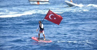 A man waves a Turkish flag while paddleboarding off the coast of Bodrum, southwestern Türkiye, July 1, 2025. (AA Photo)