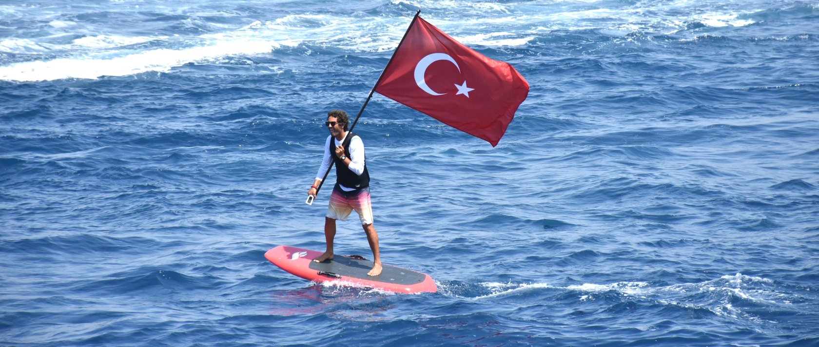 A man waves a Turkish flag while paddleboarding off the coast of Bodrum, southwestern Türkiye, July 1, 2025. (AA Photo)