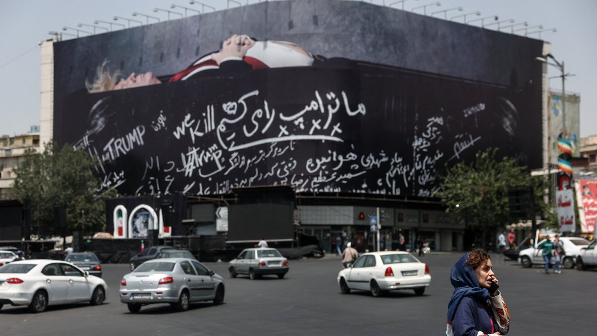 A woman talks on the phone as she stands near a billboard depicting U.S. President Donald Trump lying in a coffin, Tehran, Iran, July 23, 2026. (Reuters Photo)