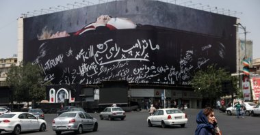 A woman talks on the phone as she stands near a billboard depicting U.S. President Donald Trump lying in a coffin, Tehran, Iran, July 23, 2026. (Reuters Photo)